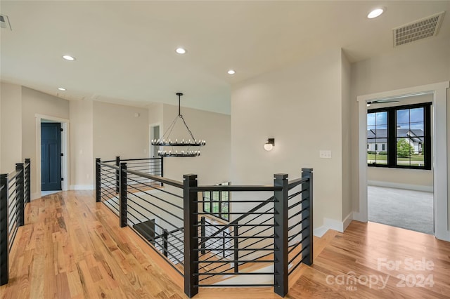 hallway with an inviting chandelier and hardwood / wood-style flooring