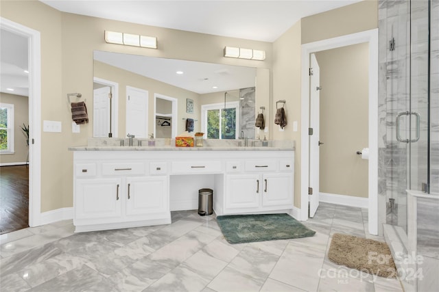 bathroom featuring a shower with door and vanity