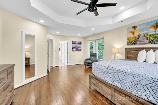 bedroom with ceiling fan, dark hardwood / wood-style floors, and a raised ceiling