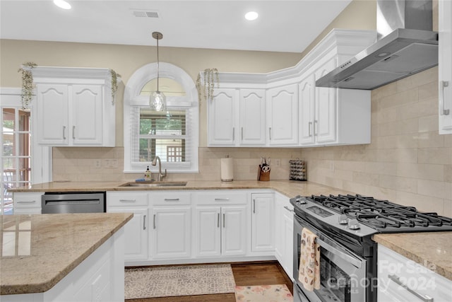 kitchen featuring pendant lighting, white cabinets, wall chimney range hood, stainless steel appliances, and sink