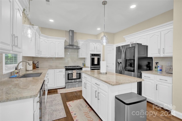 kitchen with white cabinetry, stainless steel appliances, a center island, wall chimney exhaust hood, and sink