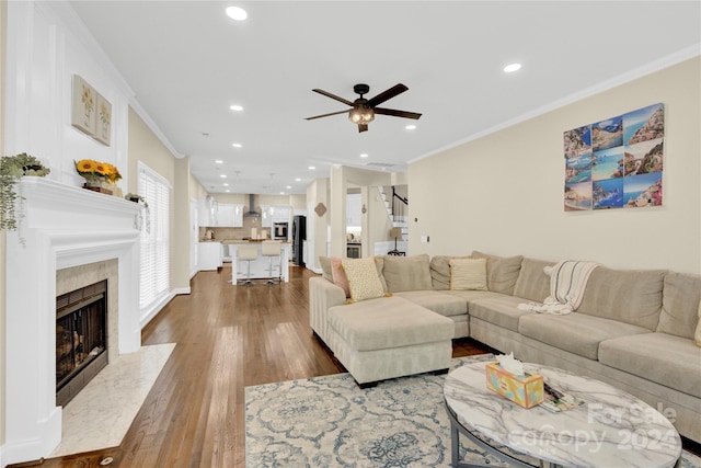 living room with ceiling fan, a premium fireplace, ornamental molding, and hardwood / wood-style floors