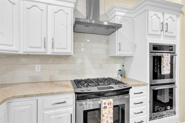 kitchen with white cabinets, appliances with stainless steel finishes, and wall chimney exhaust hood