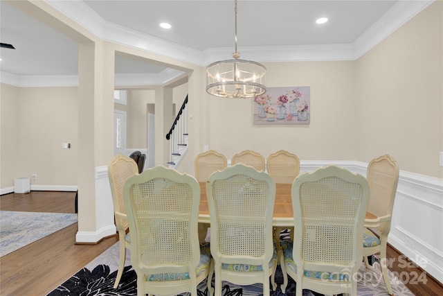 dining room with hardwood / wood-style flooring, crown molding, and an inviting chandelier