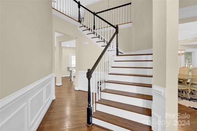 stairs with hardwood / wood-style flooring and a chandelier