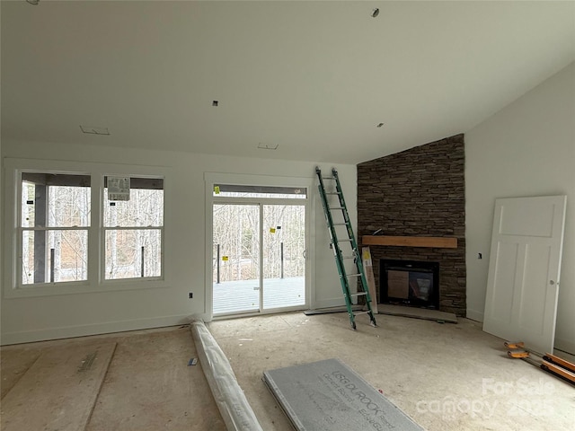 unfurnished living room featuring vaulted ceiling and a stone fireplace