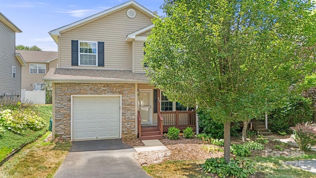 view of front of house featuring stone siding, an attached garage, driveway, and fence