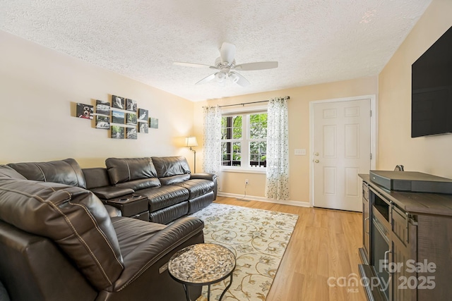 living room with a textured ceiling, ceiling fan, and light hardwood / wood-style flooring