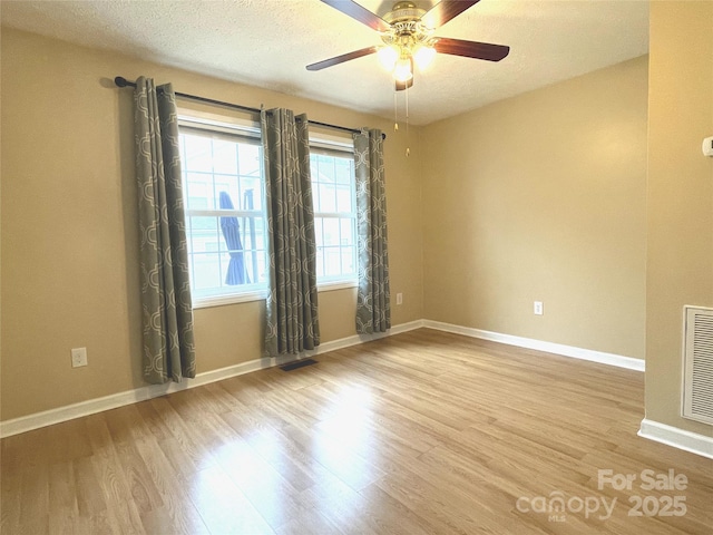 empty room featuring ceiling fan, light hardwood / wood-style floors, and a textured ceiling