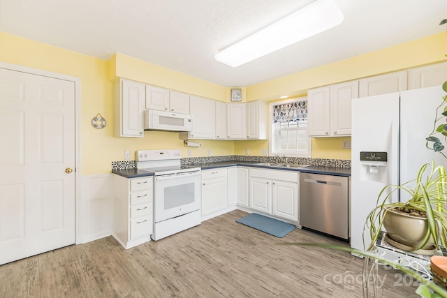 kitchen featuring sink, white appliances, light hardwood / wood-style floors, and white cabinets