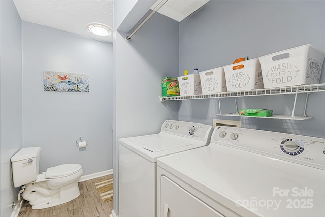 laundry area with washing machine and dryer, light hardwood / wood-style flooring, and a textured ceiling