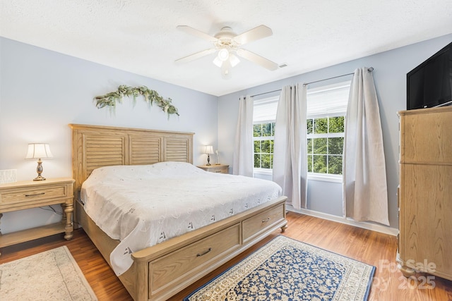 bedroom with ceiling fan, hardwood / wood-style floors, and a textured ceiling