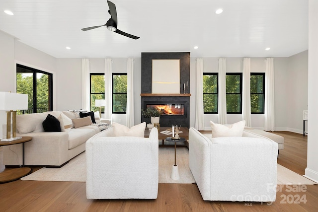 living room with light hardwood / wood-style floors, ceiling fan, and a fireplace