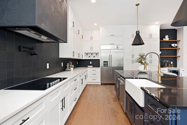 kitchen with white cabinets, wall chimney exhaust hood, stainless steel built in refrigerator, and black electric stovetop