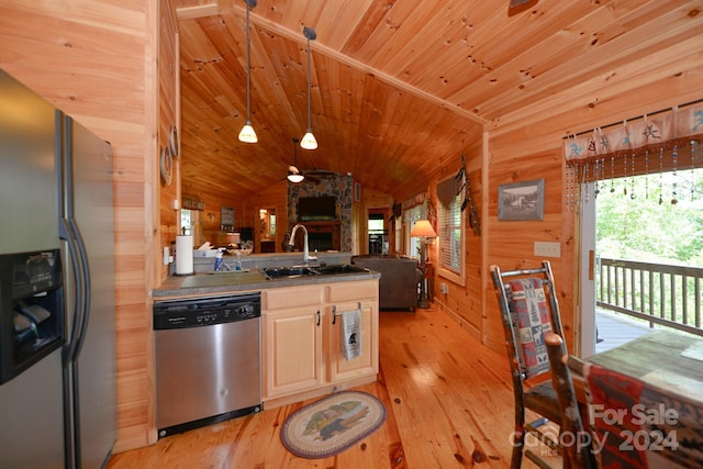 kitchen with wood ceiling, wood walls, appliances with stainless steel finishes, hanging light fixtures, and sink