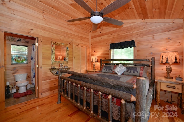 bedroom featuring lofted ceiling, connected bathroom, multiple windows, and light wood-type flooring