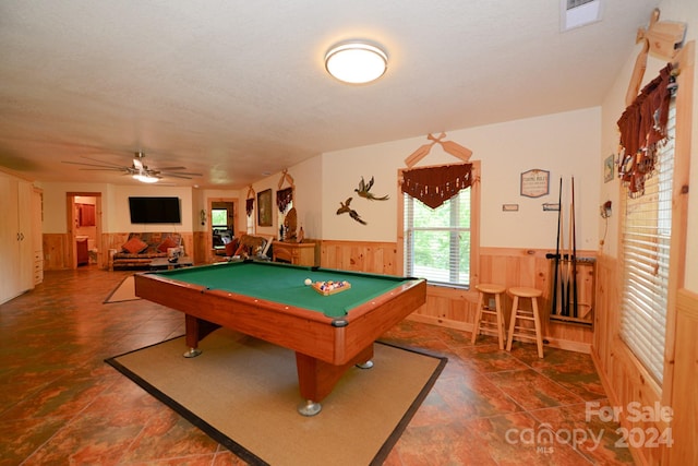 recreation room featuring wooden walls, pool table, ceiling fan, and a textured ceiling