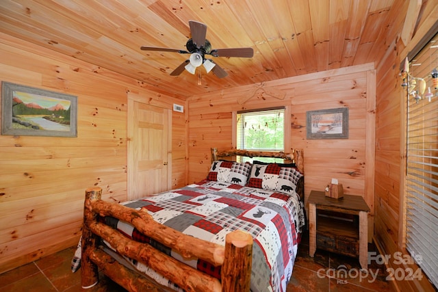 bedroom featuring dark tile patterned flooring, wood walls, and ceiling fan