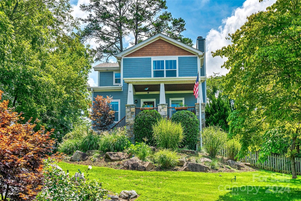 back of house featuring a lawn and covered porch