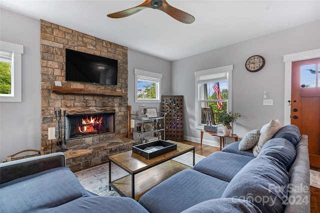 living room with ceiling fan, hardwood / wood-style floors, and a stone fireplace