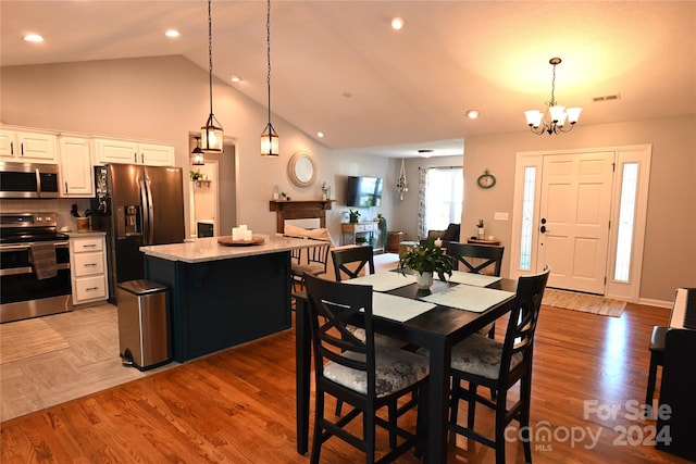 dining space with lofted ceiling, a chandelier, and hardwood / wood-style flooring