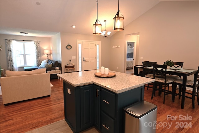 kitchen with hardwood / wood-style floors, a center island, an inviting chandelier, hanging light fixtures, and vaulted ceiling