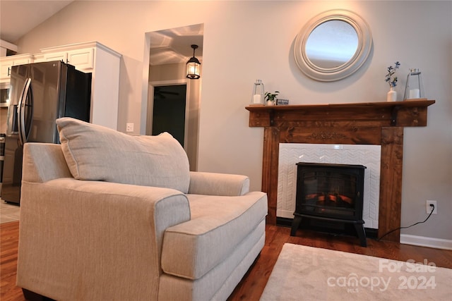 living room with vaulted ceiling, dark hardwood / wood-style flooring, and a tiled fireplace