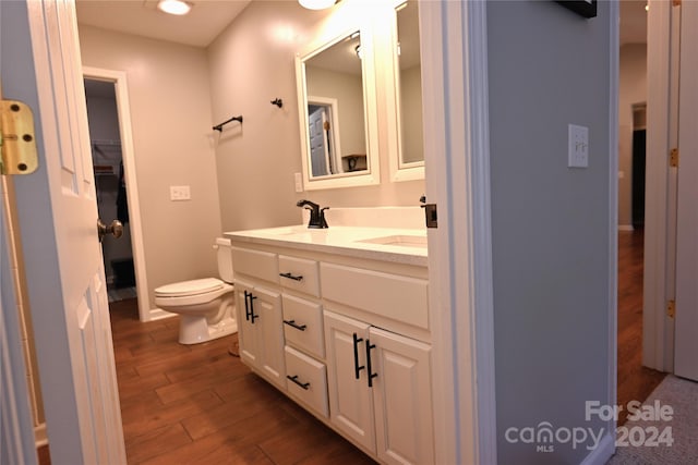 bathroom with toilet, vanity, and wood-type flooring