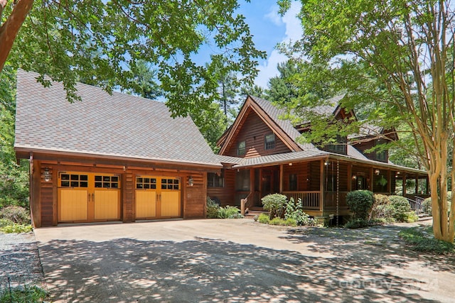 log home featuring covered porch and a garage