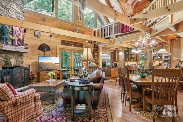 dining space with hardwood / wood-style floors, french doors, wood walls, a notable chandelier, and high vaulted ceiling