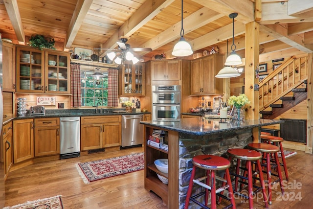 kitchen with stainless steel appliances, a kitchen island, pendant lighting, light hardwood / wood-style flooring, and beamed ceiling