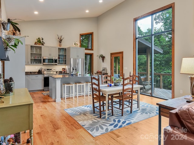 dining space with high vaulted ceiling and light wood-type flooring