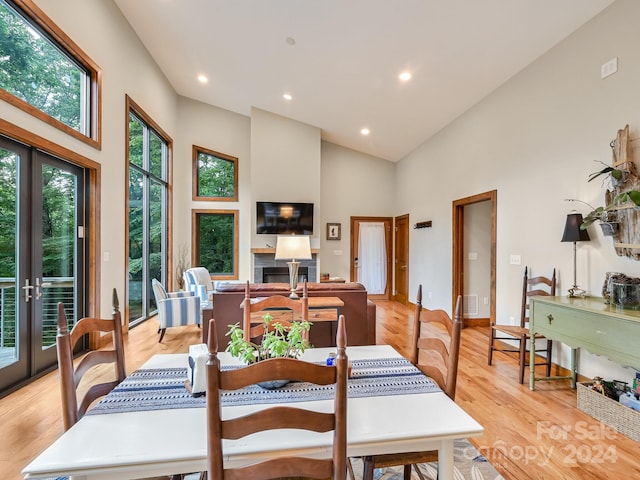 dining area with high vaulted ceiling, french doors, and light hardwood / wood-style flooring