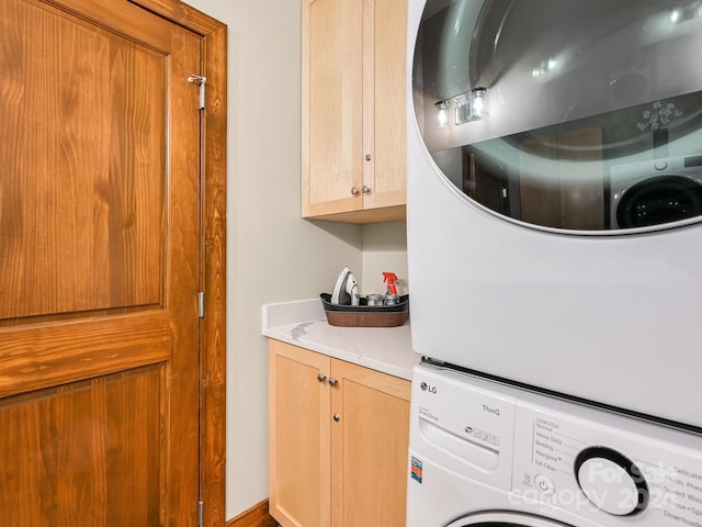 clothes washing area featuring stacked washing maching and dryer and cabinets