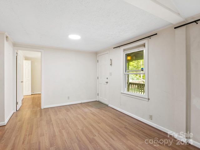 unfurnished room featuring a textured ceiling and light wood-type flooring