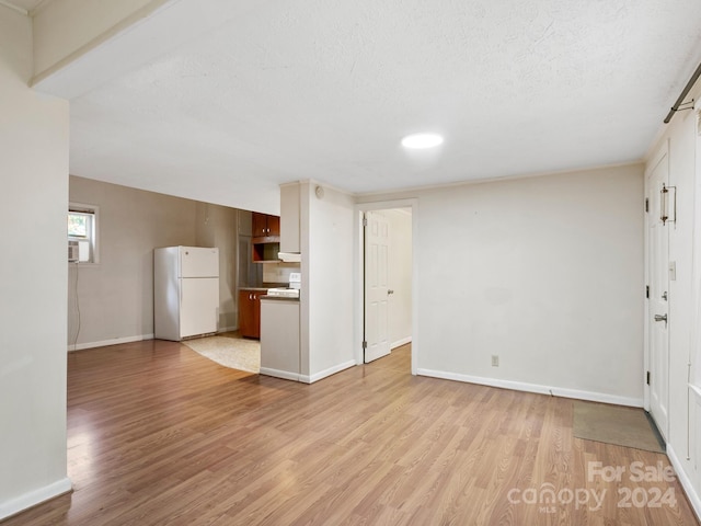 unfurnished living room featuring light wood-type flooring and a textured ceiling