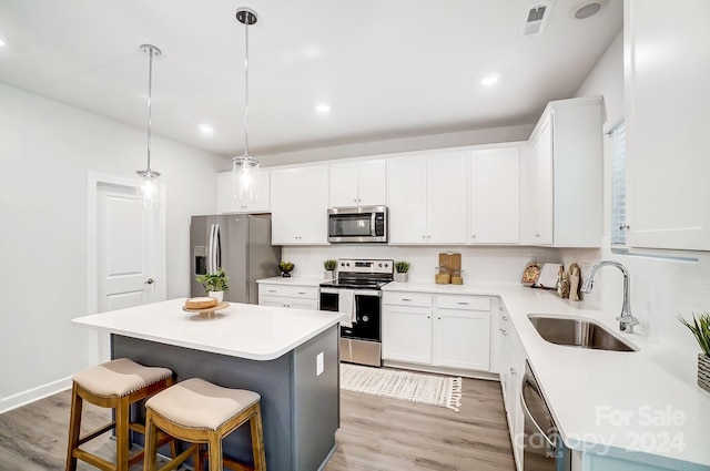 kitchen featuring a kitchen island, light hardwood / wood-style flooring, stainless steel appliances, sink, and white cabinets