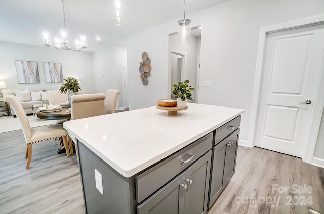 kitchen featuring pendant lighting, a center island, light hardwood / wood-style floors, and a notable chandelier