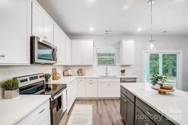 kitchen featuring a wealth of natural light, hanging light fixtures, appliances with stainless steel finishes, and white cabinets