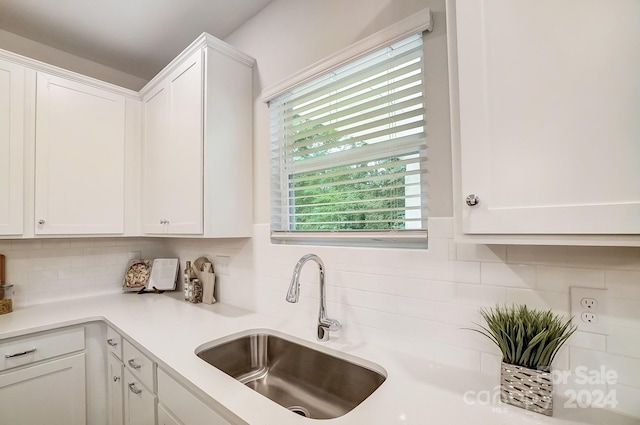 kitchen featuring tasteful backsplash, sink, and white cabinets