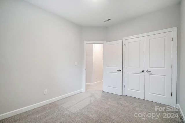 unfurnished bedroom with light carpet and a closet