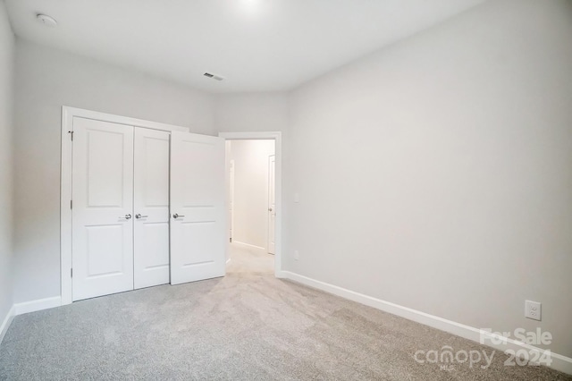 unfurnished bedroom featuring a closet and light carpet