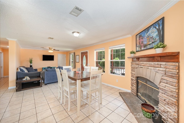 tiled dining space with ceiling fan, a fireplace, crown molding, and a textured ceiling