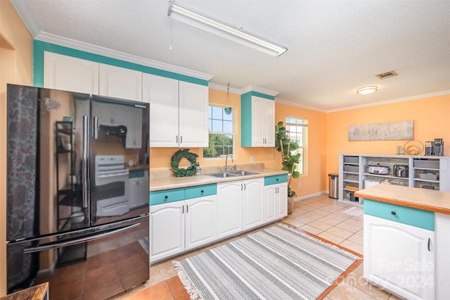 kitchen featuring black refrigerator, ornamental molding, sink, white cabinets, and light tile patterned flooring