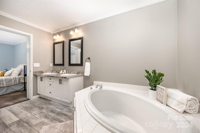 bathroom with vanity, ornamental molding, a textured ceiling, and tiled bath