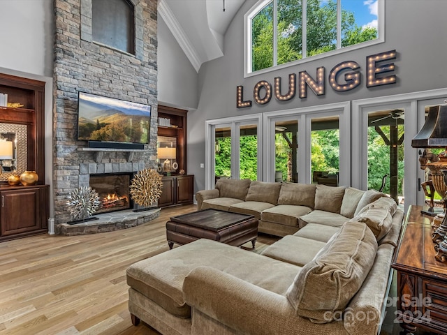 living room featuring high vaulted ceiling, light hardwood / wood-style flooring, ornamental molding, and a fireplace