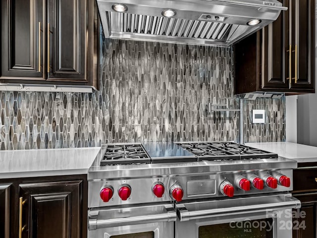 kitchen with decorative backsplash, double oven range, dark brown cabinetry, and custom range hood