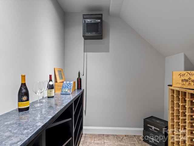 bar featuring vaulted ceiling, stone counters, and a wall unit AC