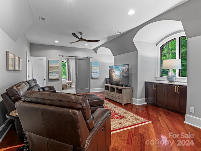 living room with vaulted ceiling, ceiling fan, a barn door, and dark hardwood / wood-style floors