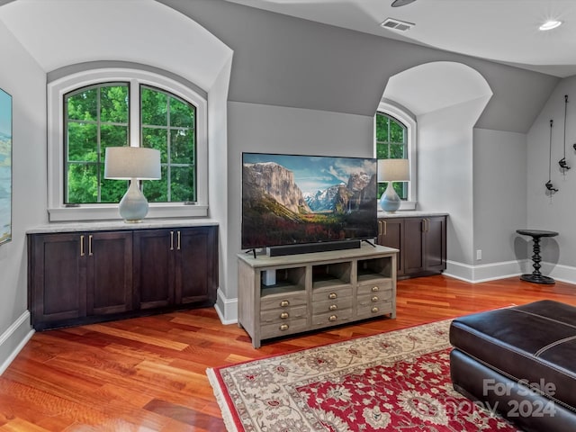 living room with plenty of natural light, light wood-type flooring, and vaulted ceiling